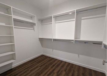A walk in closet with white shelves 